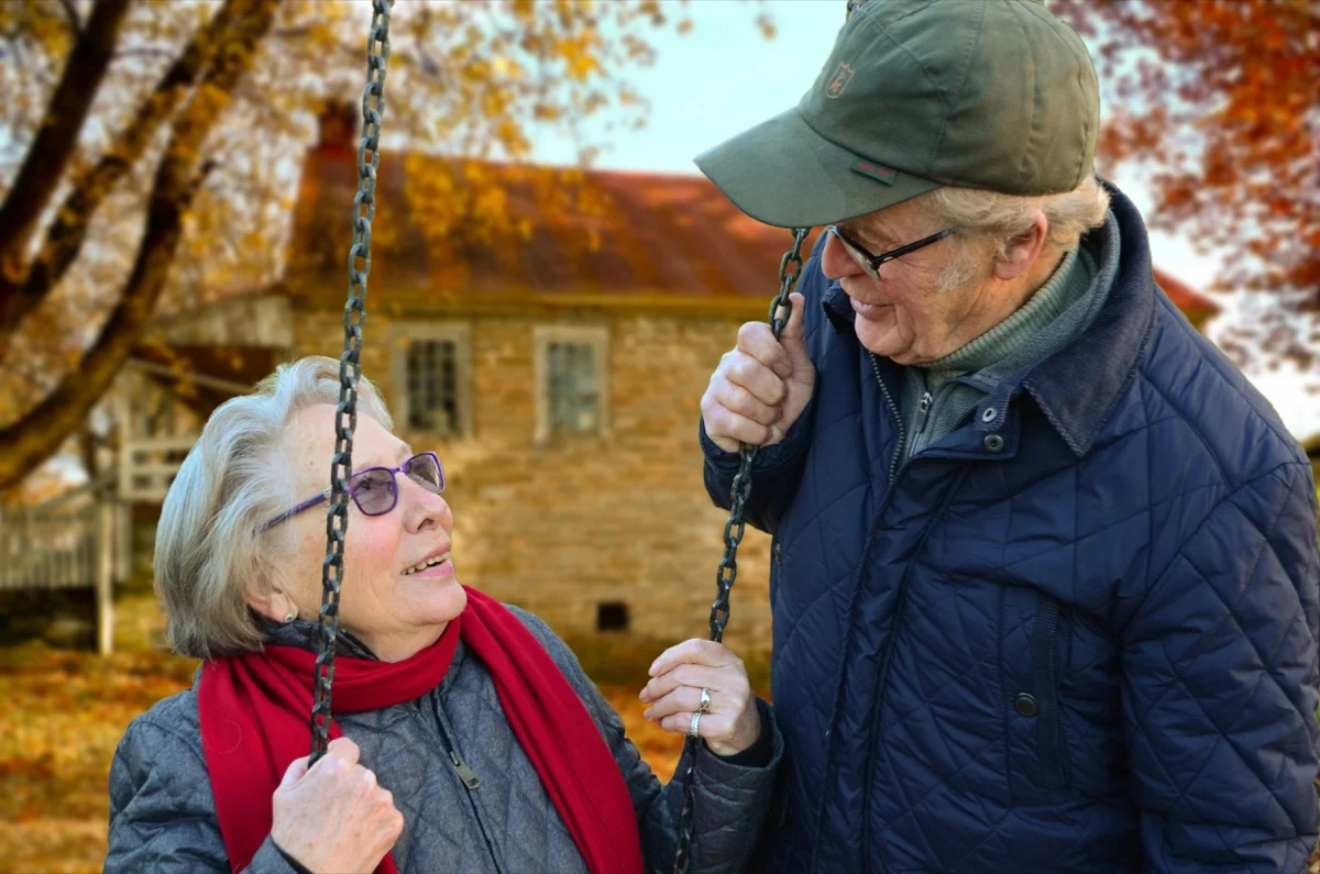 Retired couple enjoying life together on an autumn swing, financially free and stress-free