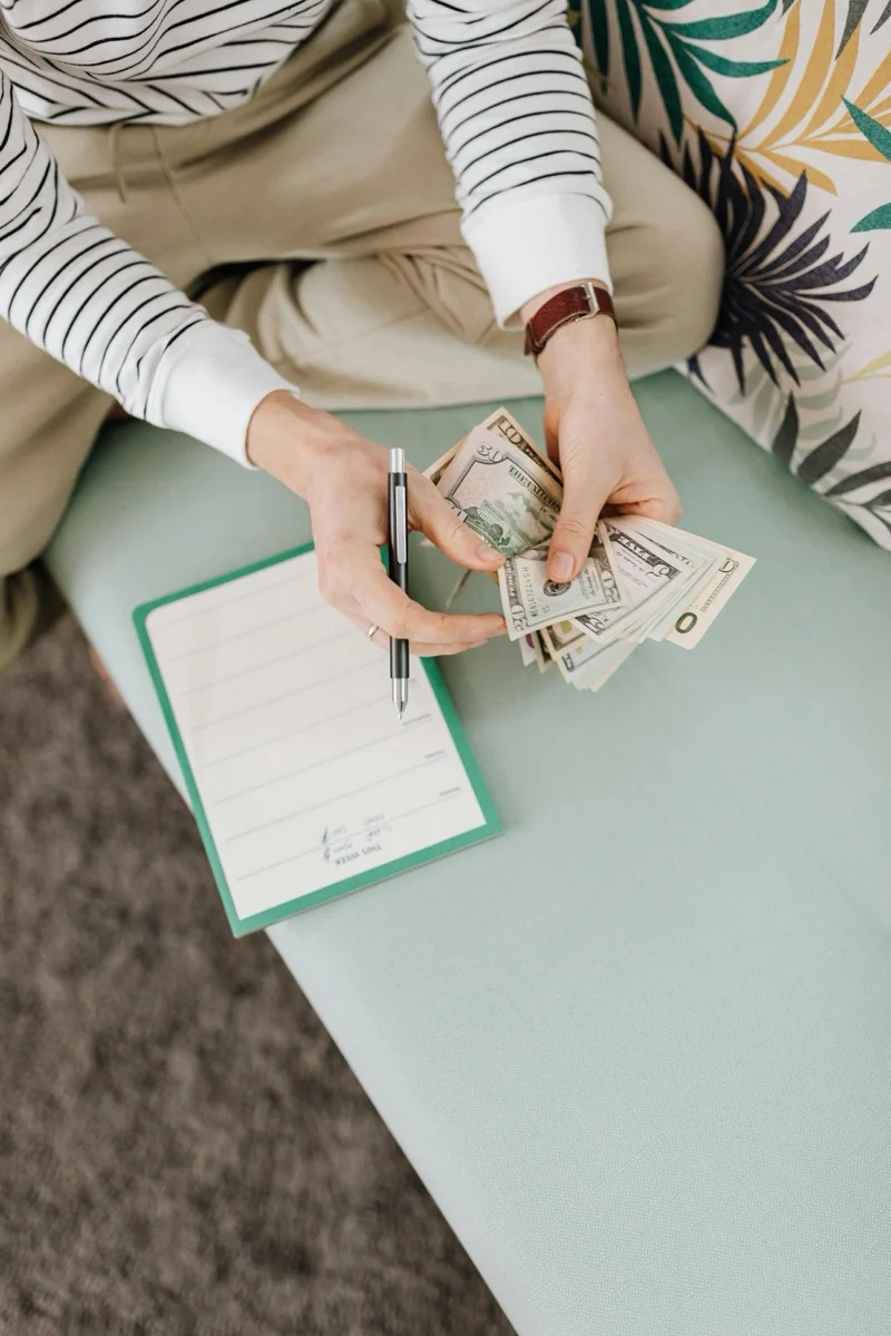 Person counting cash and planning their budget with a pen and notepad